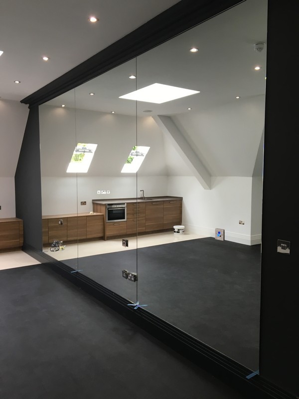 Frameless glass partition in loft conversion by Morden glaziers